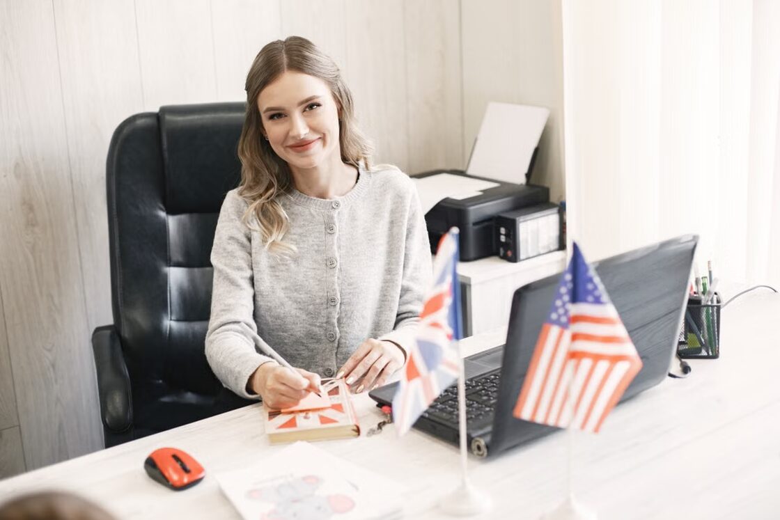 An advisory office desk with country flags, a laptop and printed forms